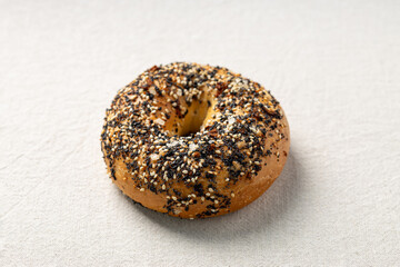 Everything bagel with sesame and poppy seeds on linen background