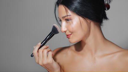Fototapeta premium Mixed-Race Beauty Woman Smiling While Holding Makeup Brush In Studio