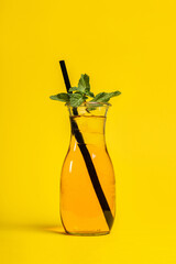 Lemon iced drink with mint and straw on yellow background