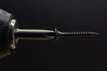 Screwdriver and screw close up isolated on black background