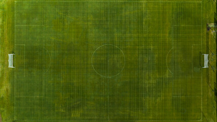 Top-down aerial shot of a green soccer pitch. Perfectly symmetrical white markings and goals are visible against the textured turf background. © Stefano Tammaro