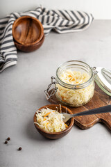 Homemade sauerkraut with carrots in a wooden bowl and glass jar.