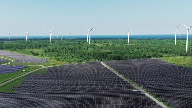 Aerial drone footage of wind turbines and solar panels at a renewable energy plant in a natural landscape near Paldiski, Estonia.