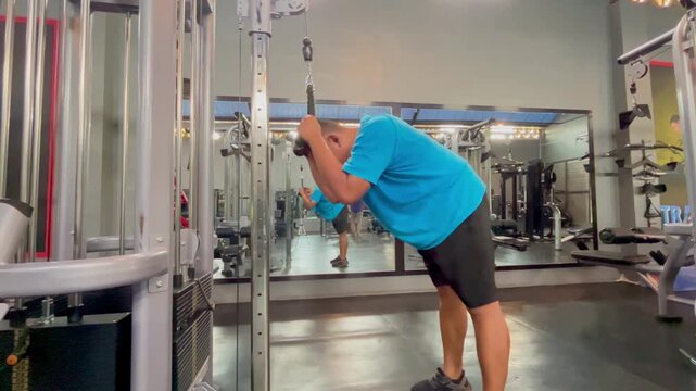 Side View of Middle-Aged Man Doing Cable Ab Crunches in Modern Gym