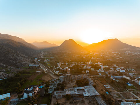 Aerial view of sun bursting over the Aravalli Range casting a golden hue across the town of Pushkar, Rajasthan, India.