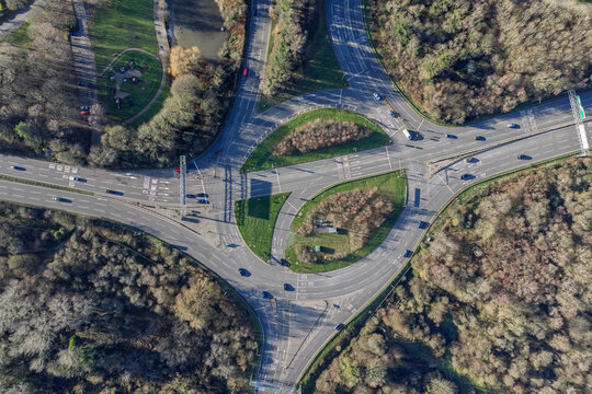 Aerial view of the intricate road network converging at a roundabout near Eastrop Park, framed by lush greenery and shadows, Basingstoke, England, United Kingdom.