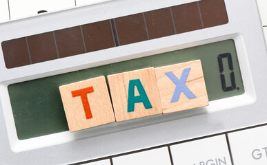 TAX word arranged with wooden letters on the calculator screen.