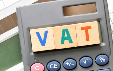 VAT word arranged with wooden letters on the calculator screen. Settlement VAT in Poland.