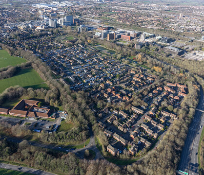 Aerial view of autumnal trees embracing residential homes near the A339, contrasting with the distant skyline of Basingstoke, England, United Kingdom.