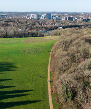 Aerial view of the lush green field contrasting with the bare trees leading to the skyline of Basingstoke's buildings, Basingstoke, England, United Kingdom.