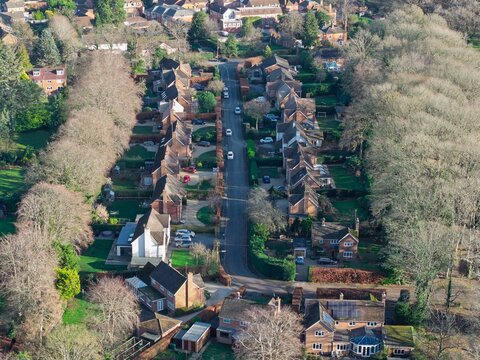 Aerial view of rooftops nestled amongst trees, a road cuts through the scene, Hartley Wintney, England, United Kingdom.