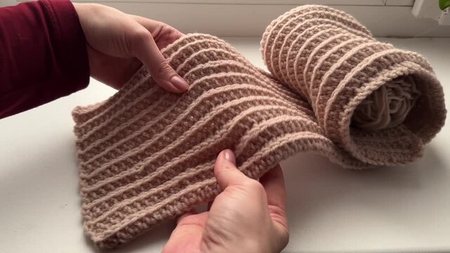 Woman examines scarf during knitting process