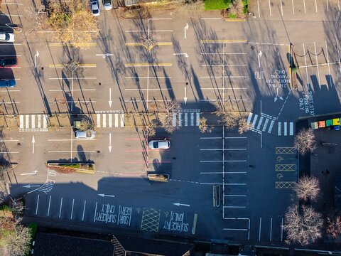 Aerial view of cars casting long shadows across the asphalt of a parking lot, with crisp white lines guiding the way, Hartley Wintney, England, United Kingdom.