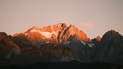 Fototapeta premium Sunrise Glow on Jade Dragon Snow Mountain over Lijiang Old Town, Yunnan, China.