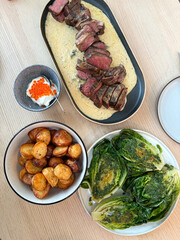 A meal of steak with cheese sauce, roast potato, and grilled lettuce.