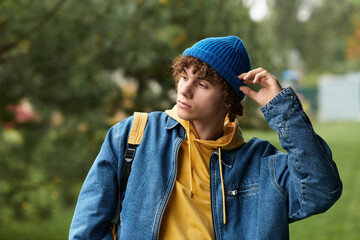 Curly teenager in blue beanie enjoys a cool autumn day outdoors