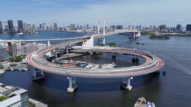 Flight over Rainbow Bridge loop interchange in Tokyo Bay with urban skyline and traffic