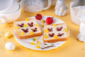 Simple Easter breakfast idea, finger press bunny rabbits jam sandwiches. Viral toasts made with pressed little fingers and strawberry or cherry jam, with fresh fruit and sugar sprinkles decor