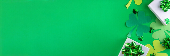 Shamrock saint patrick's day bright high-colored background, St. Patrick's holiday flatlay with party gift boxes, decor, shamrock and gold coins on green background
