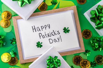 Shamrock saint patrick's day bright high-colored background, St. Patrick's holiday flatlay with party gift boxes, decor, shamrock and gold coins on green background