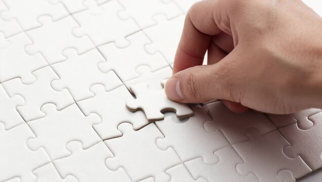 person placing piece jigsaw puzzle top white surface person hand visible right side image carefully pl
