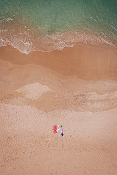 Aerial view of the contrasting turquoise sea gently kissing the golden sands, where a splash of red and white mark a peaceful beach scene, Mandurah, Western Australia, Australia.