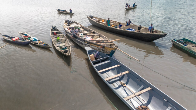 Aerial view of traditional wooden boats floating gently on the water, their weathered surfaces reflecting the soft light, Kaa Waterfront, Khana, Bori, Nigeria.