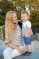 Mom and son have fun outdoors in the summer. Mother is holding the kid boy in her arms and smiling him