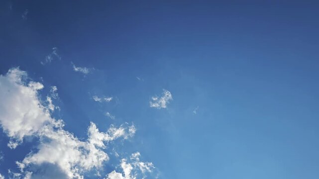 Watch as soft clouds drift, melt into the blue, and reform across a sun-drenched azure sky. This time-lapse captures the serene, organic flow of the atmosphere, featuring ample copy space.