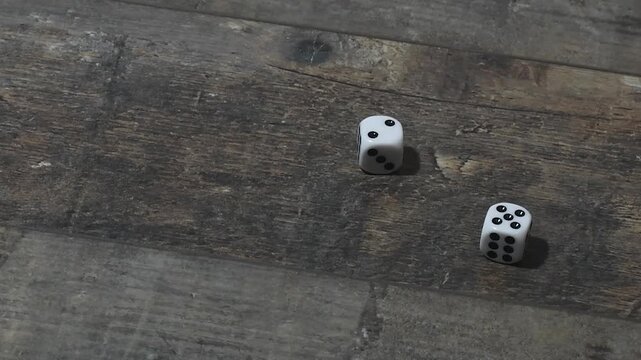 Dice rolling on a wooden table during a game - copy space