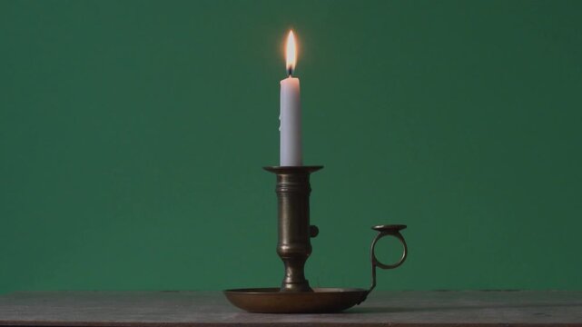 man in red places an antique candle on the table and blows out the flame