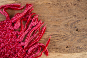 Red woven  fabric soft thick muffler scarf edge on oak wooden background
