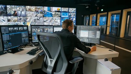 Medium shot of a technician using AI software on multiple screens to monitor live broadcast quality in a control room environment