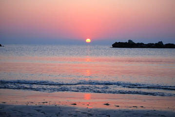 Die Sonne steigt aus dem Meer und f&auml;rbt den Himmel rosa.