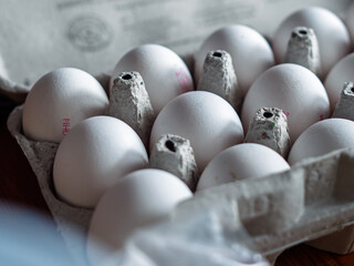 Fresh White Eggs in a Cardboard Carton on a Wooden Table