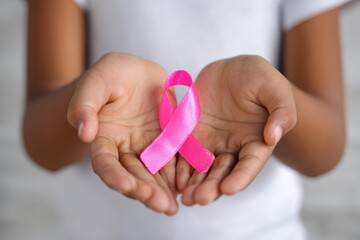 Breast cancer awareness pink ribbon held in caring hands