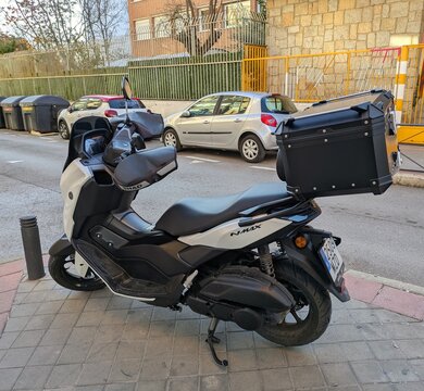 Vista lateral de moto scooter Yamaha Nmax 125 con portaequipajes y guantes de manillar estacionada en Madrid, Espa&ntilde;a, 6 de enero de 2026