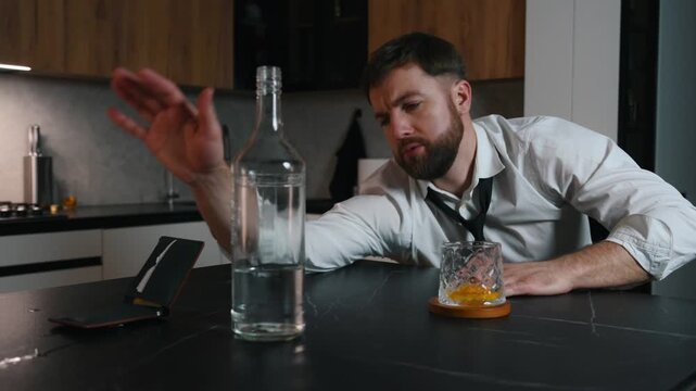 Drunk man sitting in a dark room with a bottle of vodka and drinking. Problems with depression alcohol addiction