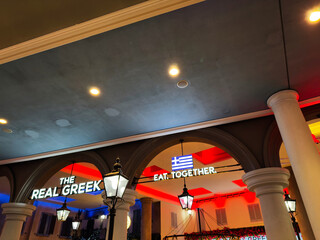 Naklejka premium The Real Greek Eat Together signage under arches at Manchester UK restaurant, illuminated at night