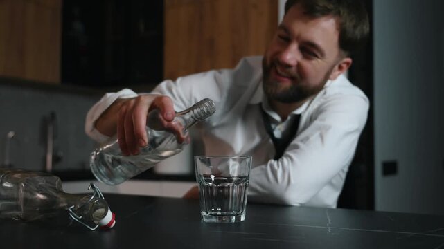 Drunk man sitting in a dark room with a bottle of vodka and drinking. Problems with depression alcohol addiction
