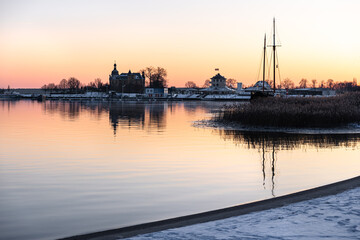 Fototapeta premium Sunset at Goitzsche Lake with view toward the promenade and marina, snow-covered landscape, orange-red sky, winter lakeside scenery in Central Germany.