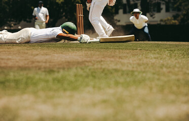 Cricket player diving to crease to avoid run out during intense match play