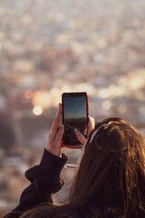 Girl photographing Barcelona skyline with smartphone