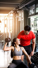 A male trainer is demonstrating the method and steps for a dumbbell exercise to a woman in the gym, Exercise concept, health maintenance, Horizontal image, vertical image.