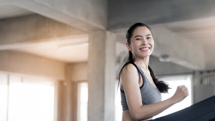 A beautiful young woman with a smiling face is in a gym. The concept is about exercise and health care. (Horizontal and vertical images available).