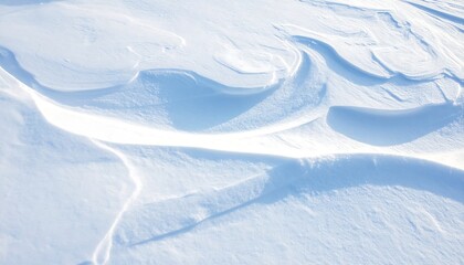 Drifting snow forms soft waves and shadows in the winter sun, creating a peaceful, abstract landscape