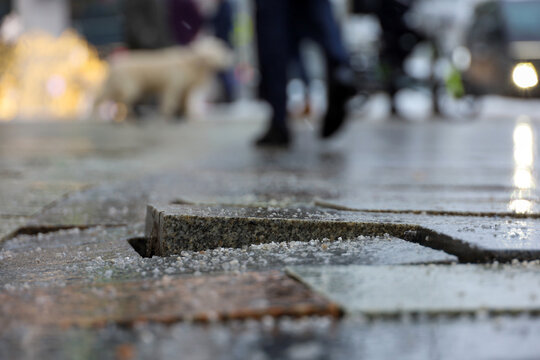 Cobbled city street in winter. Stone tiles sprinkled with deicing mixture