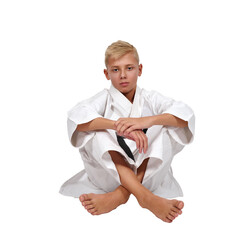 Young karate athlete in white gi and black belt sitting cross-legged