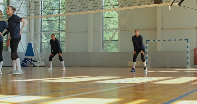 The girls receive the ball from their opponents and return it, scoring a point.