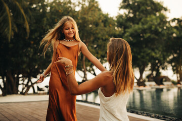 Mother and daughter bonding in a tropical setting by the pool